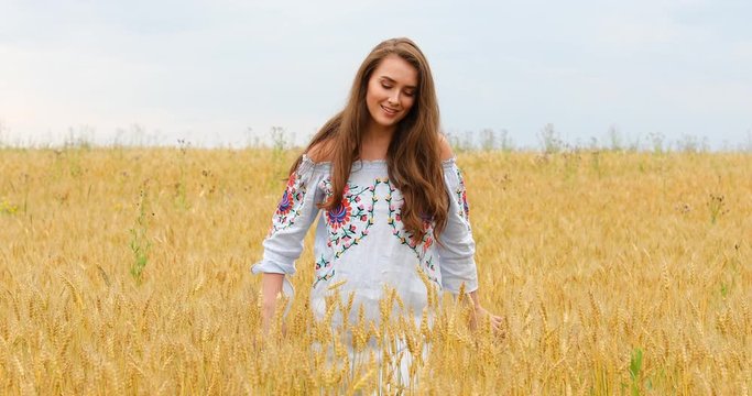 Young beautiful girl posing against a wheat field background