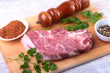 Raw beef steak with spices Leaves of coriander on wooden cutting board. Ready for cooking.