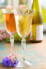 Cold summer wines, white and rose, served in beautiful glasses on the fresh air, outdoor in the green garden with flowers, sunny day