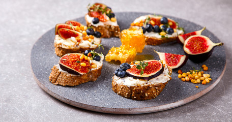 Bruschetta with cheese, figs , thyme and berry blueberrie with honey.Snack a sandwich with cream cheese.selective focus