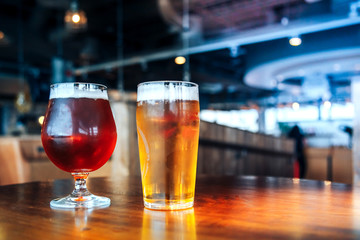 Two glasses of light and dark beer on a wooden table in a cafe or restorant