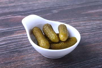 Bowl with pickled gherkins, cucumbers on wooden background close up. Pickles.