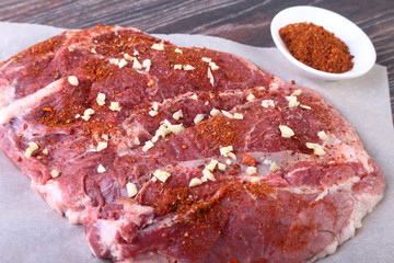 Raw pork steaks on wooden board with herbs, garlic and spices ready for cooking. Selective focus.