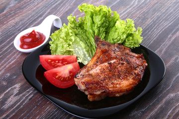grilled pork chops with tomato, leaves lettuce and ketchup on plate.