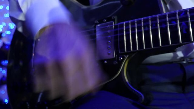 Close up of jazz guitarist on stage playing the electro-guitar with mediator. Bright stage lights flashing, panoramic shooting, Slow Motion Effect .