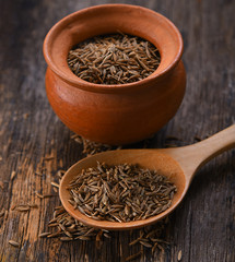 Cumin seeds in spoon wood on wooden background