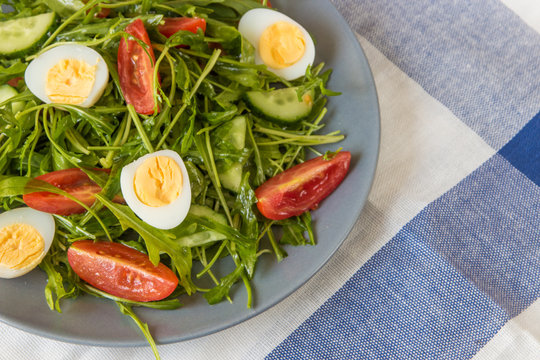 Fresh green salad with arugula, tomatoes, eggs and cucumber