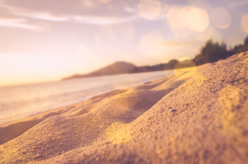 Tilt-shift blur tropical sunset sand beach with bokeh sun light abstract background.