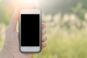 Copy space hand using smart phone and sun light in nature green park background. Travel adventure lifestyle and business economic concept.
