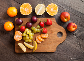 A set of different fruits on a dark, wooden background. Top view, space for text