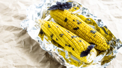 Two corn cobs baked in foil with basil © svitlini