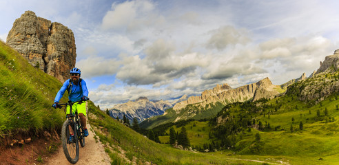 View of cyclist riding mountain bike on single trail in Dolomites, Cinque Torri, South Tirol, Italy