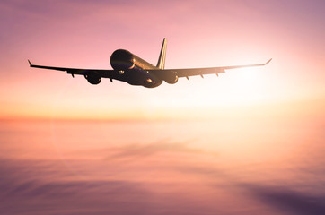 Airplane flying over blur tropical beach with smooth wave and sunset sky abstract background.