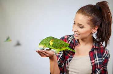 Fototapeta premium parrot sitting on a girls hand and kissing her .