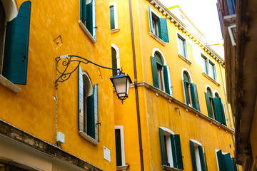Fototapeta na wymiar Building yellow wall with green windows Behind Lamp post on street view, idea for your background
