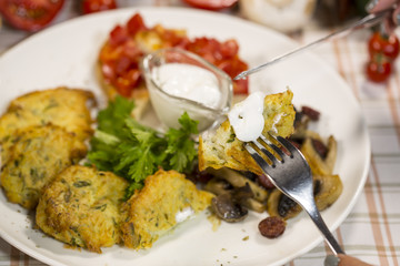 Potato pancakes with mushrooms, sour cream and tomatoes. Breakfast from fried potato drills. Classic Slovene breakfast