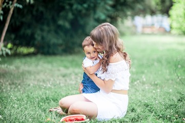 Mother and young son played on grass. Happy family walks in the Park. Mom and young son eating watermelon. Picnic. Summer.