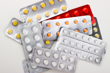 tablets on a white background in white, yellow, orange, a syringe, a needle, an ampoule of medicine