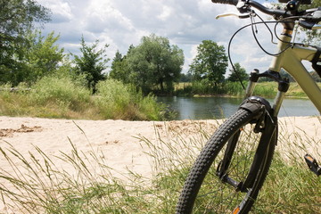 Naklejka premium Sandy beach on the river bank with a bicycle in the foreground during a walk 