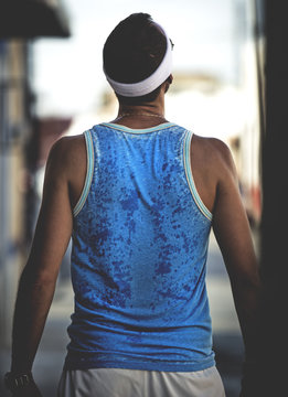 Rear view of a man wearing a sports vest and a sweatband.