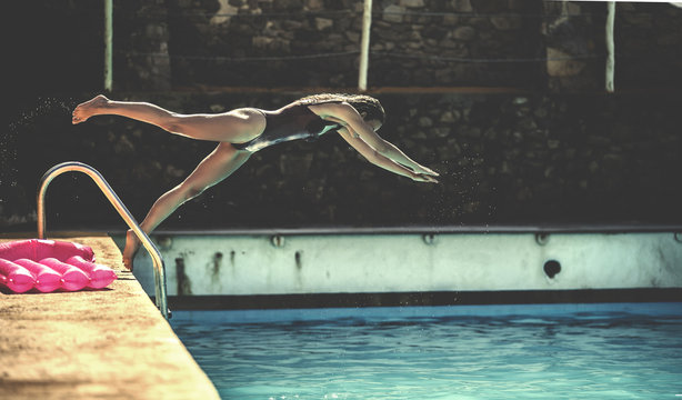 A young woman wearing a swimsuit diving into a swimming pool.