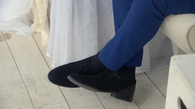 Men's shoes, dangles her feet. Suit.