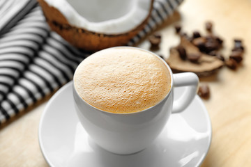Tray with cup of tasty coconut coffee and nut on table