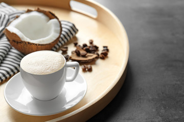Tray with cup of tasty coconut coffee and nut on table