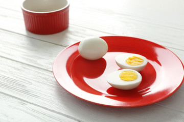 Red plate with hard boiled eggs on wooden table. Nutrition concept