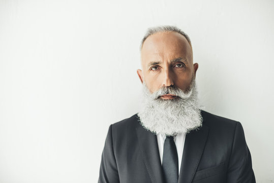 Handsome Stylish Senior Businessman Leaning Back On White Wall