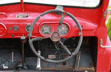Steering wheel of old red rusted truck.