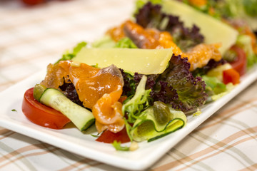 Salad with salmon, parmesan cheese, lettuce and rocket salad. Salad with fish.