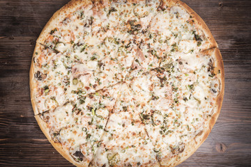 Hot pizza on a brown wooden background