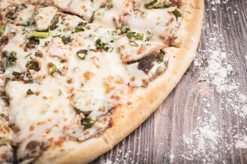 Pizza with mushrooms and pickled cucumbers close-up on a brown wooden background