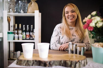 Young woman barista working in coffee shop. Smiling girl at the bar in the cafe