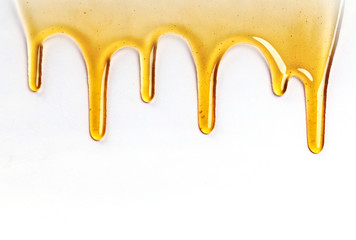 Dripping golden sweet honey flowing down the frame from the top over white with copyspace and text
