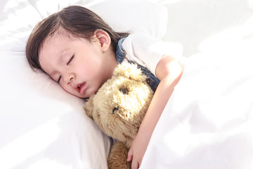 Little asian girl sleeping with her toy teddy bear