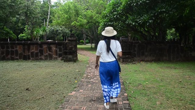 Travelers thai woman walking and visit ancient building and ruins of Kamphaeng Phet Historical Park is an archeological site and Aranyik Area in Kamphaeng Phet, Thailand