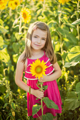 Happy litlle girl holding sunflower on the field in summer. Portrait of a smiling girl in the field of sunflowers