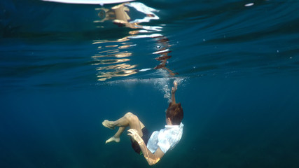young man sinking into the sea