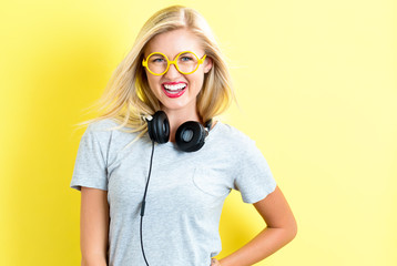 Happy young woman with headphones on a yellow background