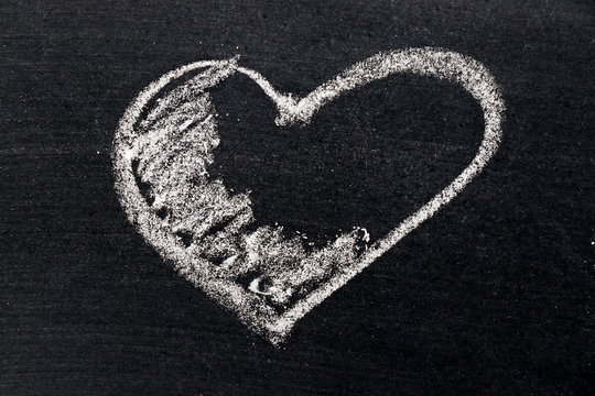 White chalk drawing in heart shape on black board background use for decoration in valentine, love, couple or engagement concept