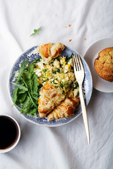 Breakfast in bed. Scrambled eggs with cheese croissants, raspberry muffin and black coffee. Morning treat concept. Composition with copy space.