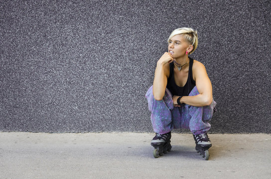 Girl crouched next to a wall in roller skates, black wall copy space
