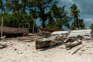 wooden handmade boat with mast on fishing village shore in Zanzibar