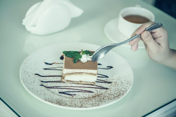 Italian dessert tiramisu with mint with cup of tea on the table.