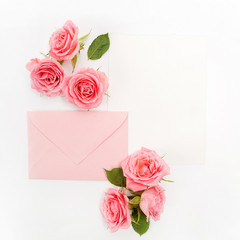 Envelop with white card and rose background. Top view. Flat lay