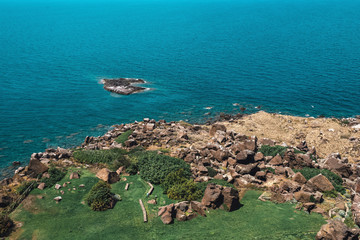 High angle view of coastal shore with rocks and grass.