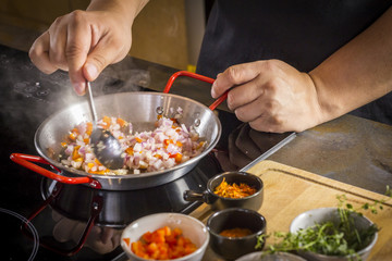 Chef is frying food ingredient for cooking paella