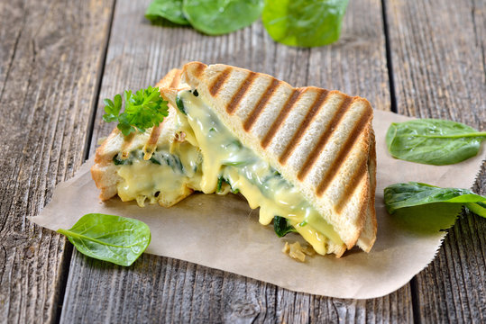 Im Kontaktgrill gepresstes italienisches Panini mit jungem Blattspinat, Zwiebeln  und Käse - Pressed and toasted double panini with spinach, onions and cheese served on sandwich paper
